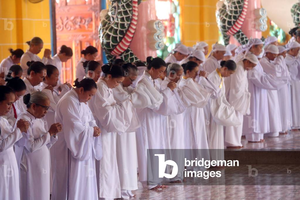 Cao Dai Holy See Temple. Praying devout women, ceremonial midday prayer. Thay Ninh. Vietnam