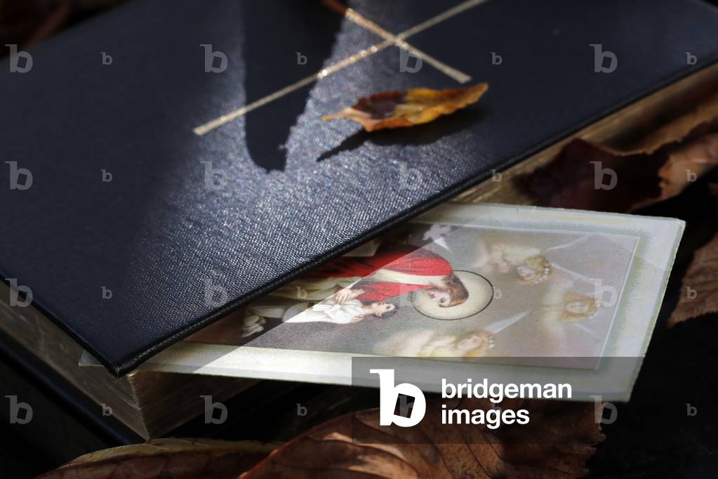 Bible and Holy image on dry fallen autumn leaves. Faith and spirituality. Jesus.  France.