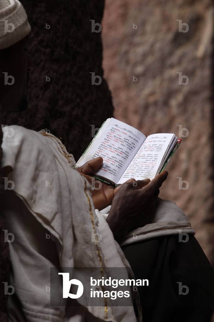 Man reading scriptures outside Bet Medhane Alem church in Lalibela, Lalibela, Ethiopia