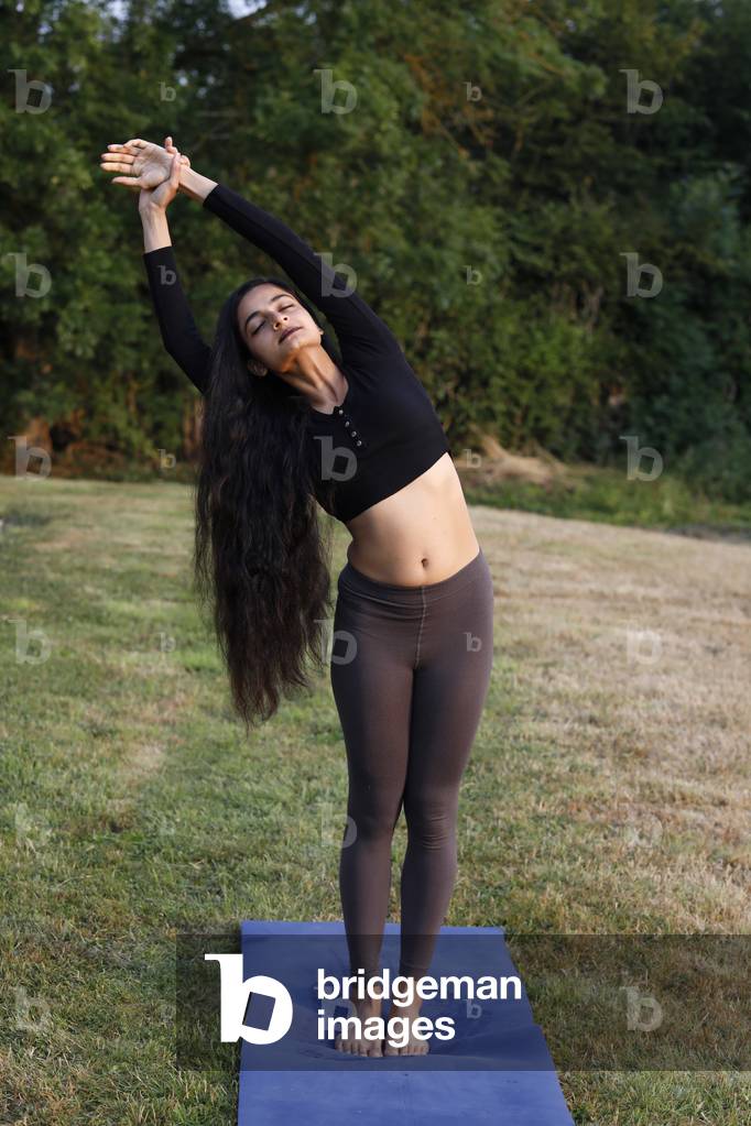 Young woman doing yoga in a garden in Eure, France
