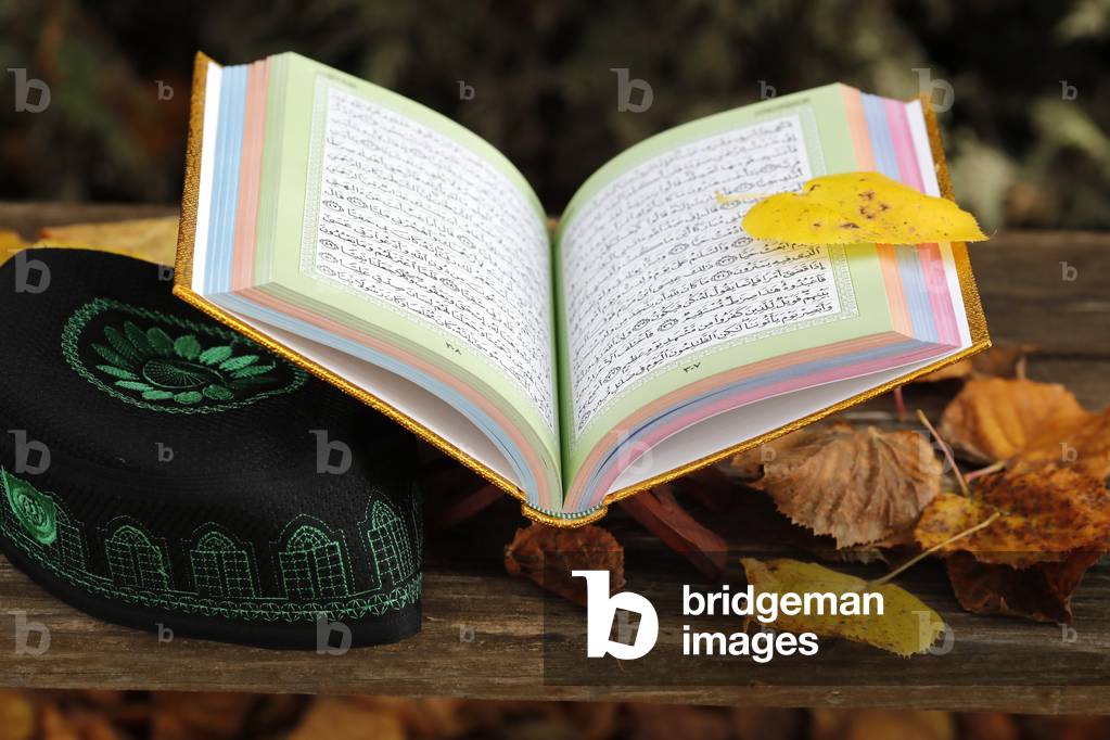 An open Holy Quran  on wood stand  and a kufi.  France.