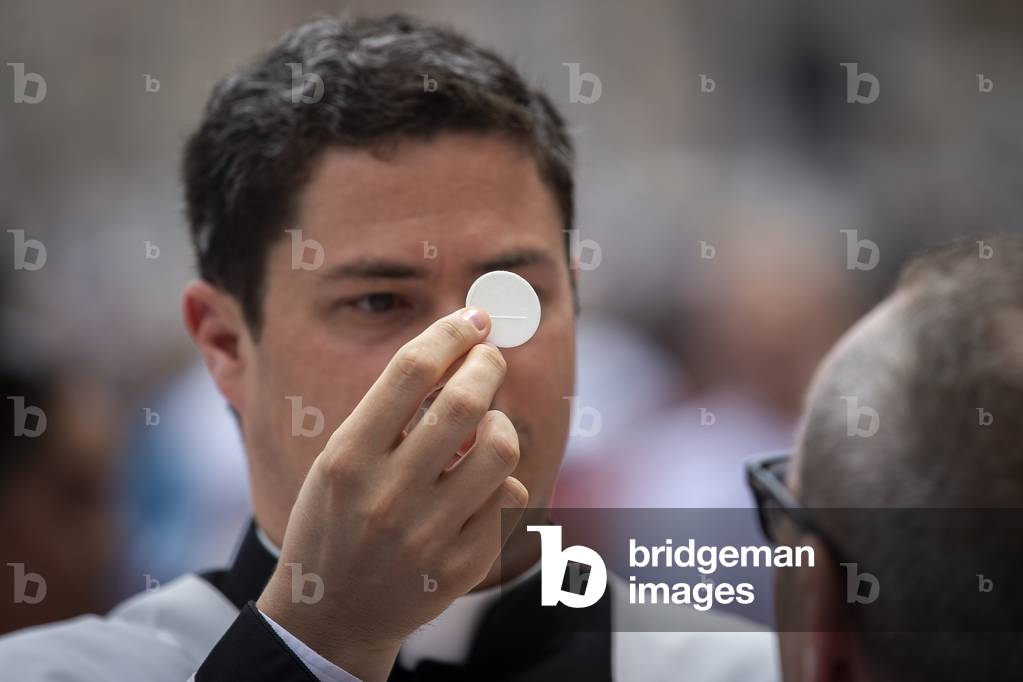 A priest gives holy communion during Pentecost Holy Mass in St. Peter's Square, at the Vatican, 2019 (photo)