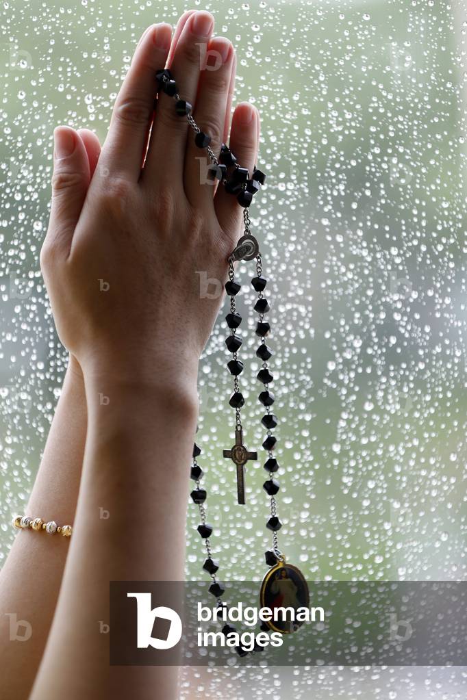 Catholic woman praying with rosary beads. Close-up.