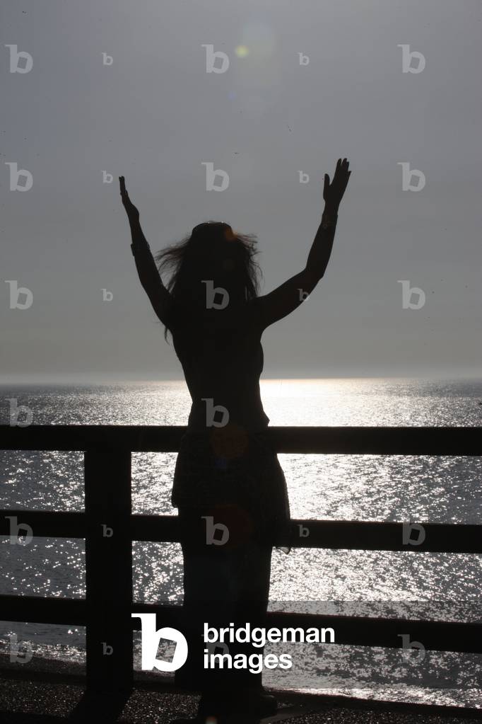 Woman praying at sunset. Etretat France
