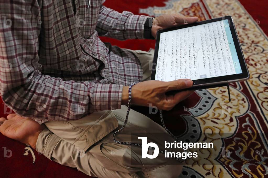Muslim reading a digital Quran on a tablet, 2019 (photo)