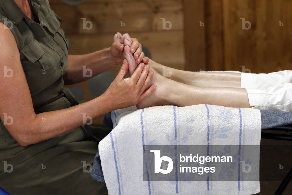 Traditional chinese medecine. Foot reflexology. Masseur pushing on special points on the foot, massage treatment France.