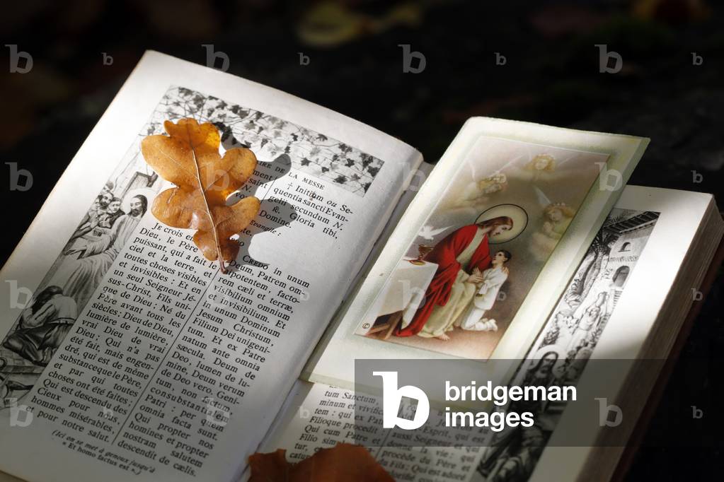 Missel and Holy image with dry fallen autumn leaf. Faith and spirituality. Jesus.  France.