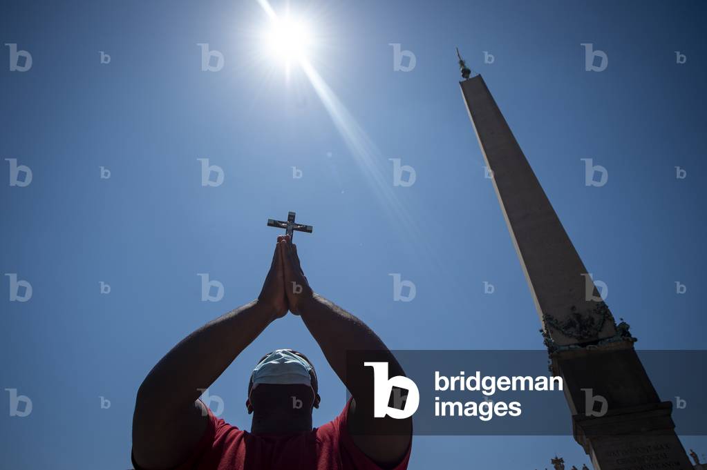 A man raises a cross during Pope's weekly Angelus prayer at St. Peter's Square in The Vatican, on June 28, 2020