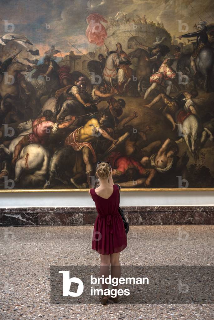 Young woman taking a picture of a Padovanino painting at Pinacoteca di Brera, Milan, Italy (photo)