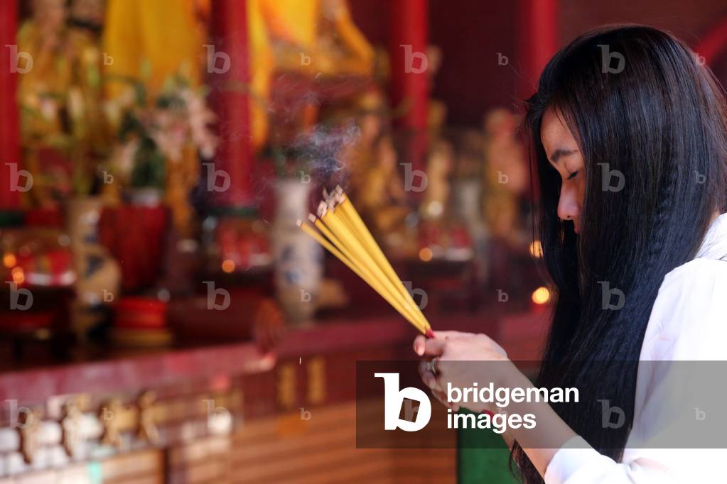 Tempio taoista di Chua On Lang. Adoratore buddista. Bastoncini di incenso acceso. Ho chi Minh City. Vietnam