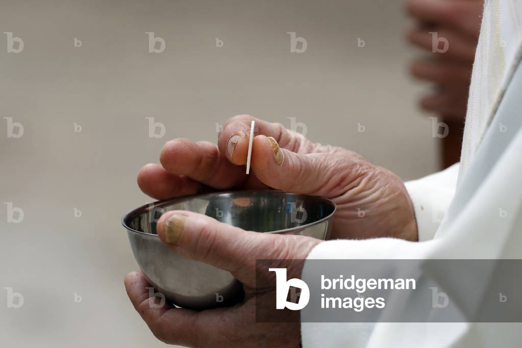 Catholic church during covid-19 epidemic. Sunday mass. Priest giving Holy Communion.  Sanctuary of La Benite Fontaine. France.