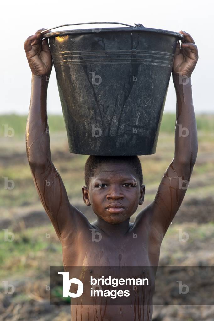 Boy watering a field in Karsome, Togo, 2019 (photo)