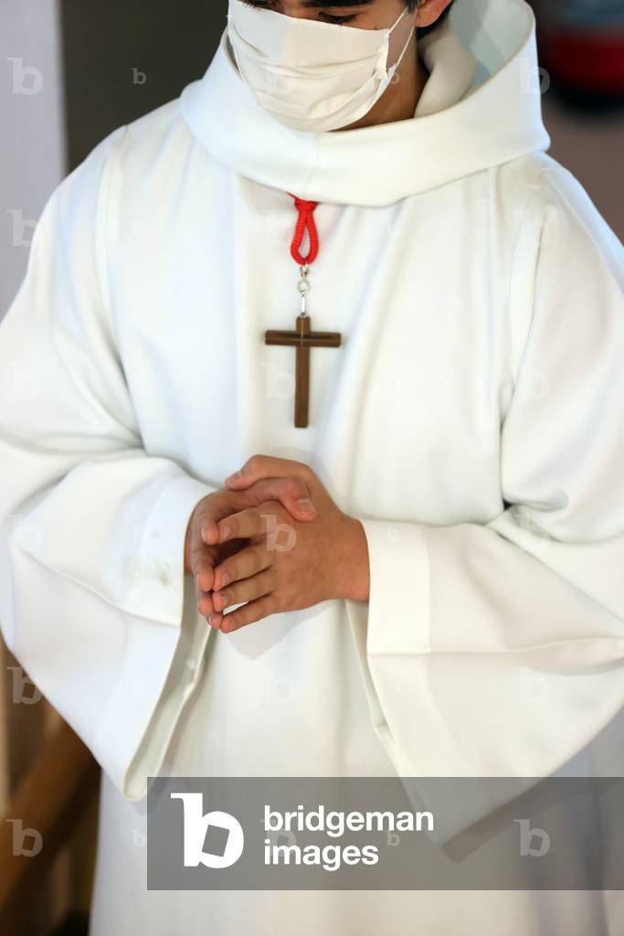 Catholic church during covid-19 epidemic. Sunday mass.  Altar boy at eucharistic celebration.  France.
