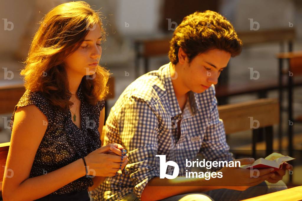 Teenagers praying and reading the Bible in a church, Galatone, Italie