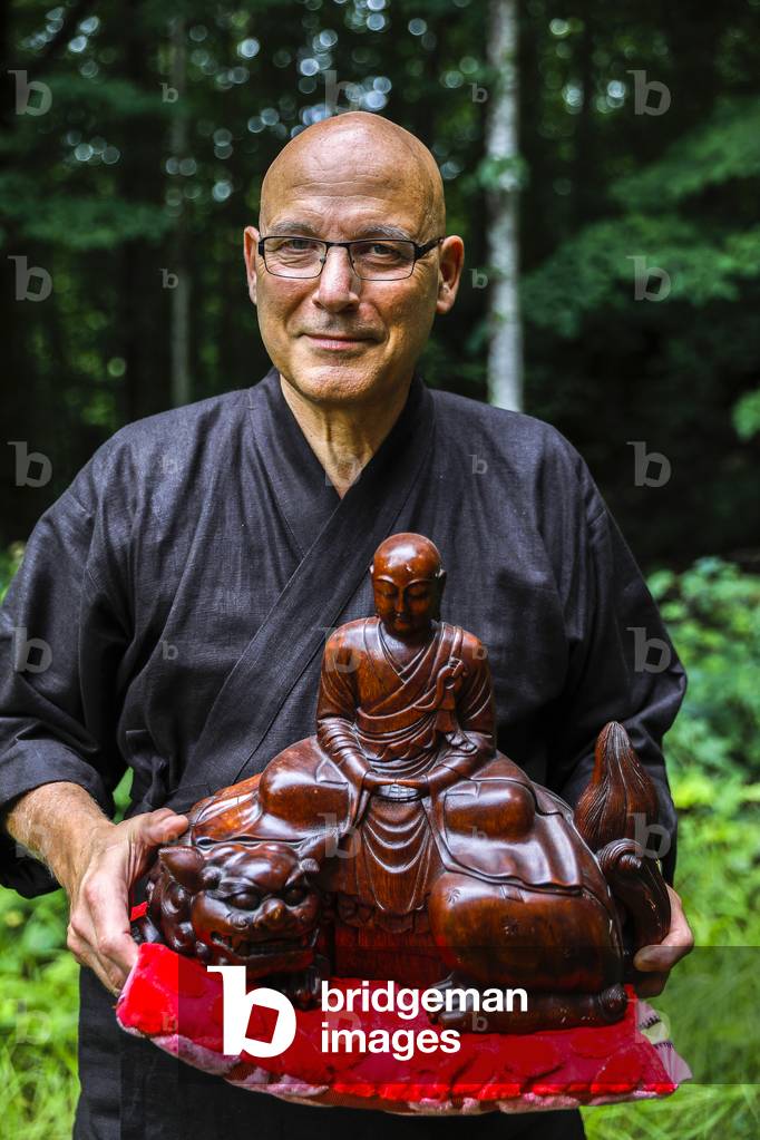 Zen buddhist monk carrying a Buddha statue at Orval trappist abbey, Belgium.