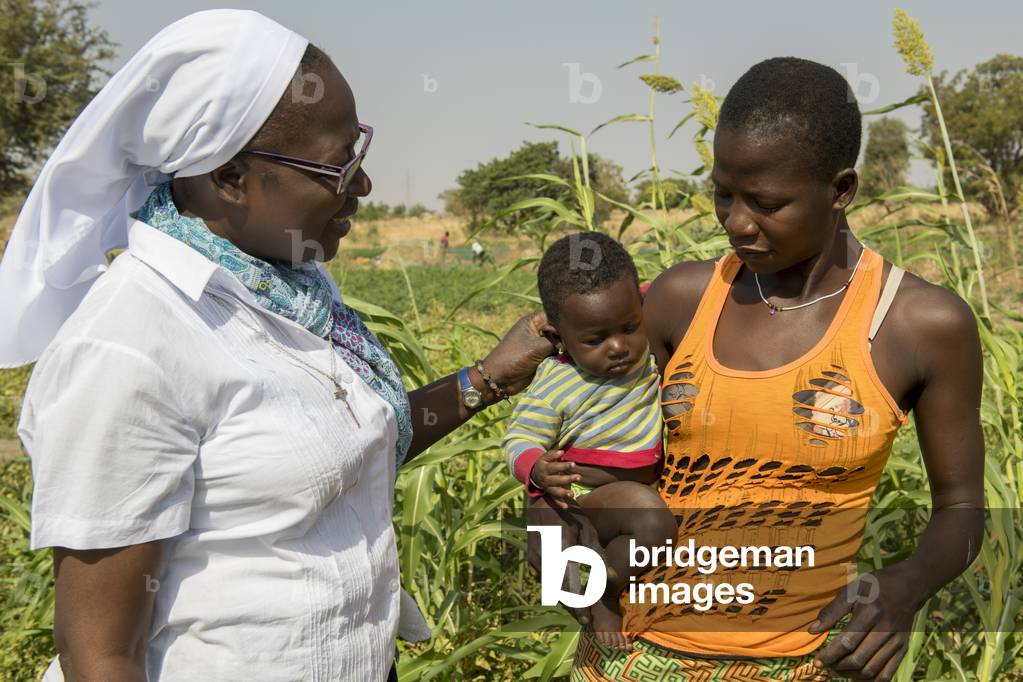 Sister Marie Stella talking to a peasant teenage mother in a field where she is working near Dapaong, Togo.