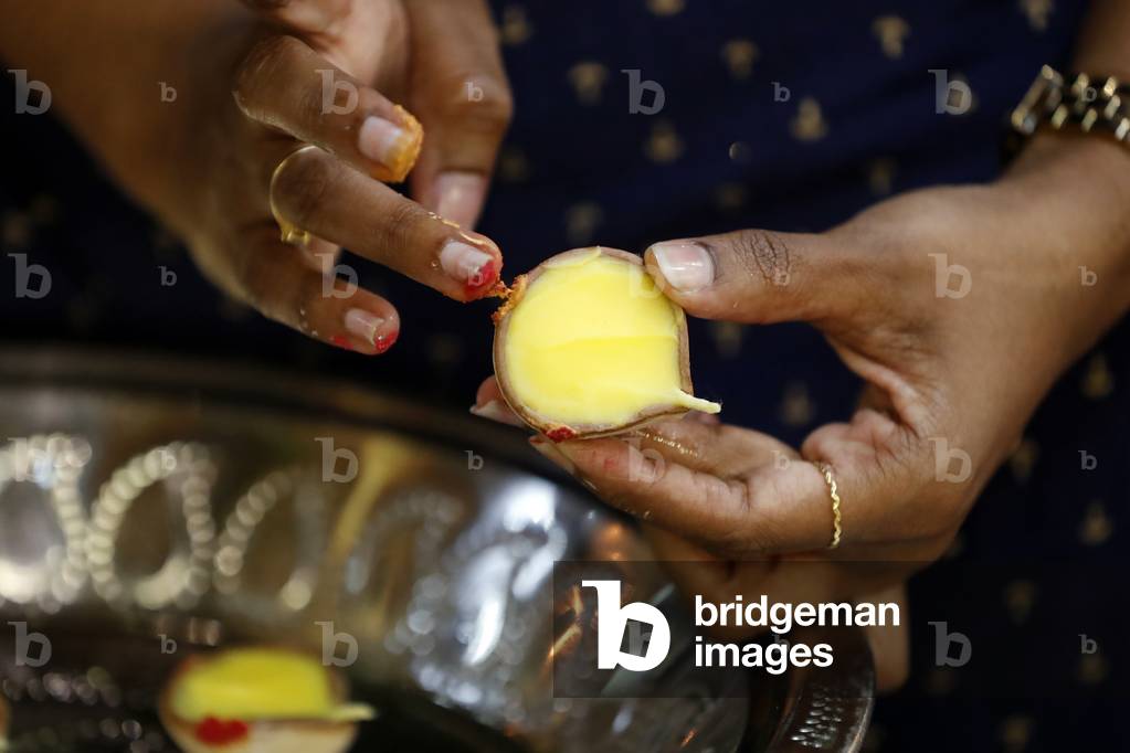 Sri Mahamariamman Hindu Temple, Woman using a butter lamp for rituals and offerings to deities, Kuala Lumpur, Malaysia (photo)