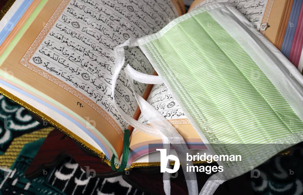 Religion and coronavirus (COVID-19), Quran and disposable surgical mask (photo)