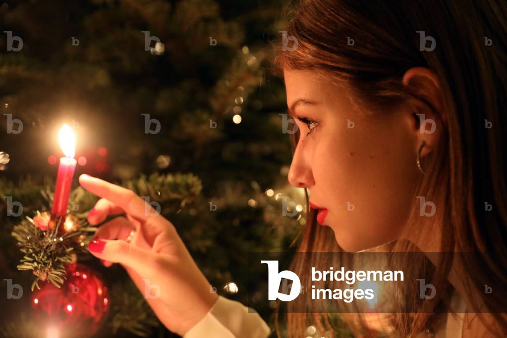 Girl looking at a candle on a Christmas tree, Geneva, Switzerland (photo)