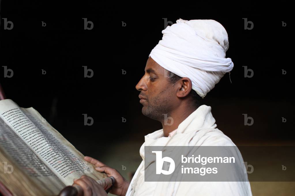 Priest reading a Bible at StYimrhane Kristos cave church, , Ethiopia
