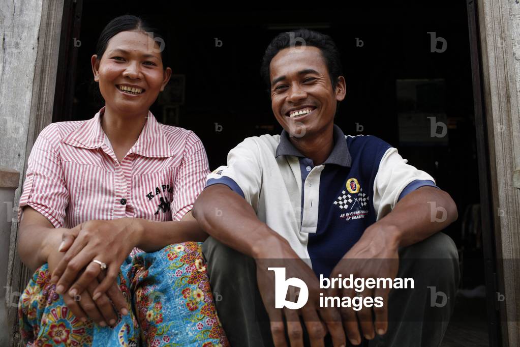 Am Tron, a client of HKL microfinance, outside her home with her husband Tamang Cambodge
