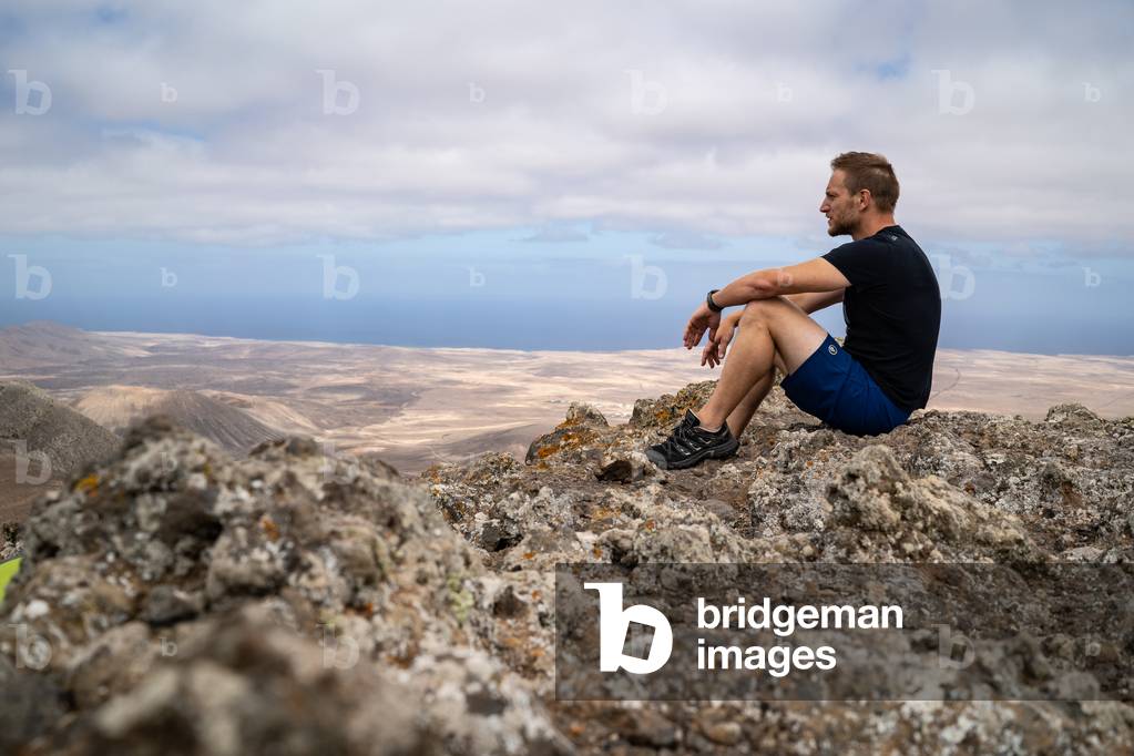 Man sitting on rocks in Fuerteventura landscape, Canarias Islands, Spain (photo)