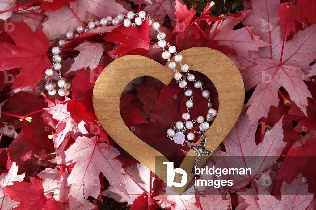 Wooden heart and catholic rosary on fall red leaves. Autumn.  France.