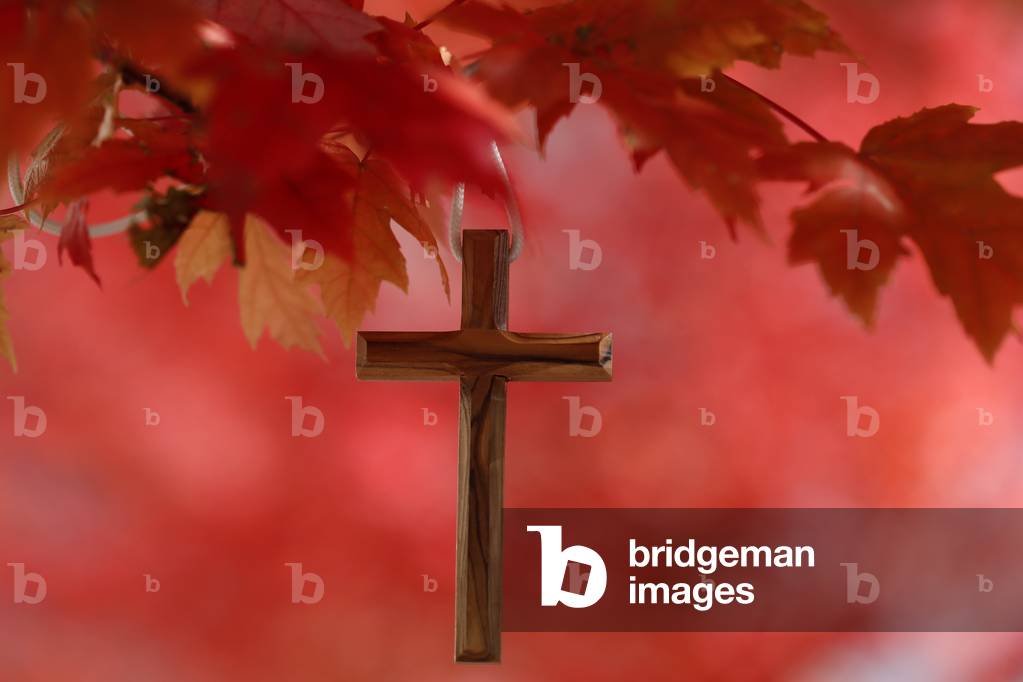 Christian cross hanging on a tree branch with red leaves. Autum.  France.
