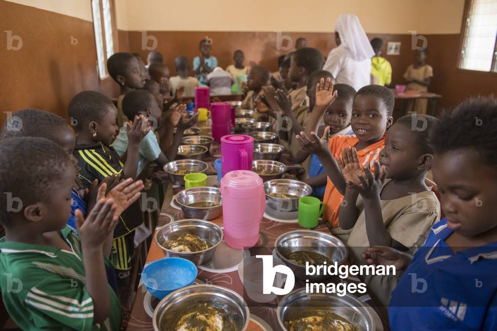 Orphanage run by Vivre dans l'Esperance (living with hope) NGO in Dapaong, Togo. Children praying and singing before lunch.