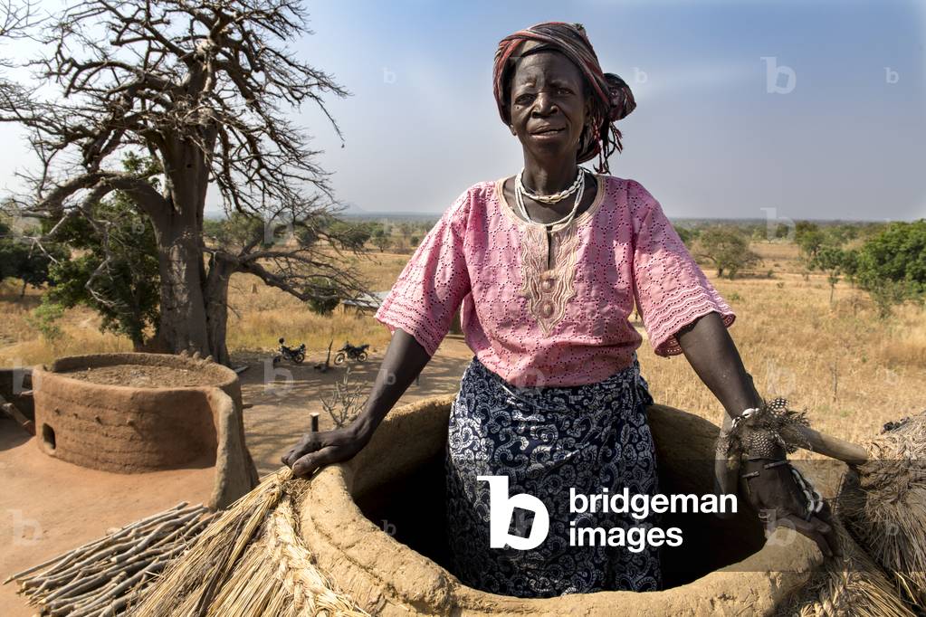 Old Batammariba woman  standing in the granary on top of her 