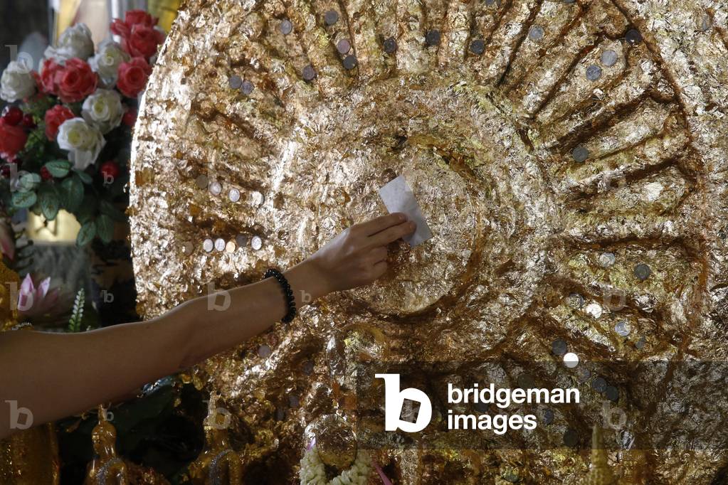 Faithful offering gold leaves in Wat Mahathat, Phetchaburi. Thailand