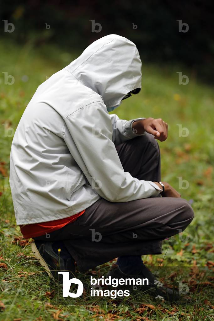 Young man praying alone in nature.  France.
