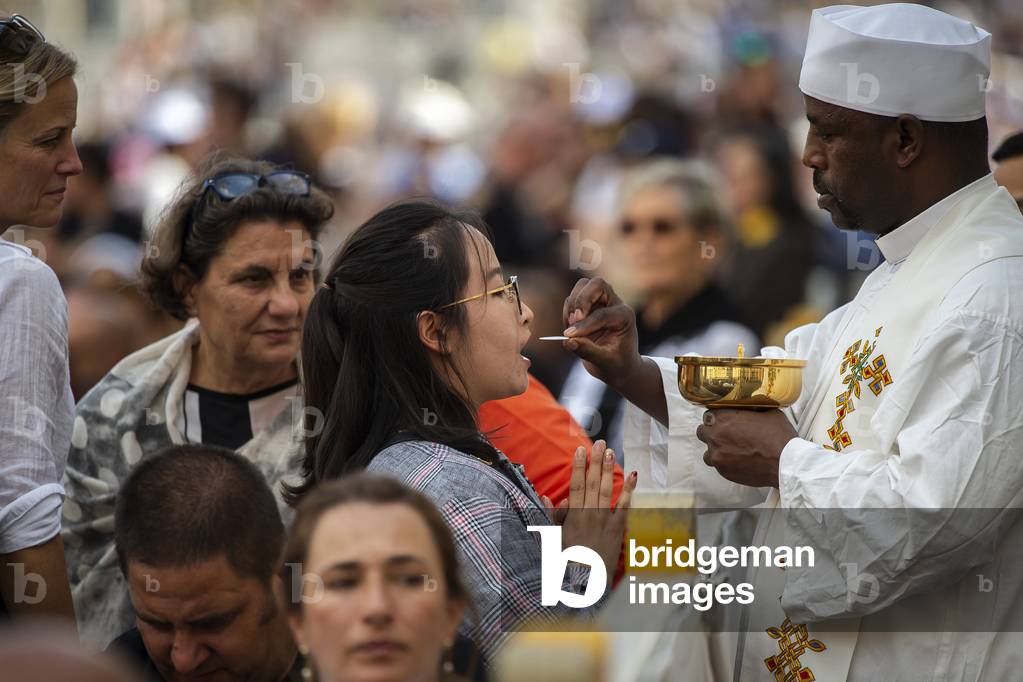 A Priest gives holy communion to the faithful during Pope Francis Holy Mass in St. Peter's Square, at the Vatican.