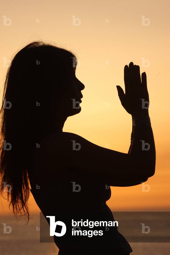 Woman praying at sunset. Etretat France