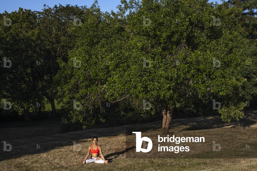 Yogini meditating in a garden in Eure, France