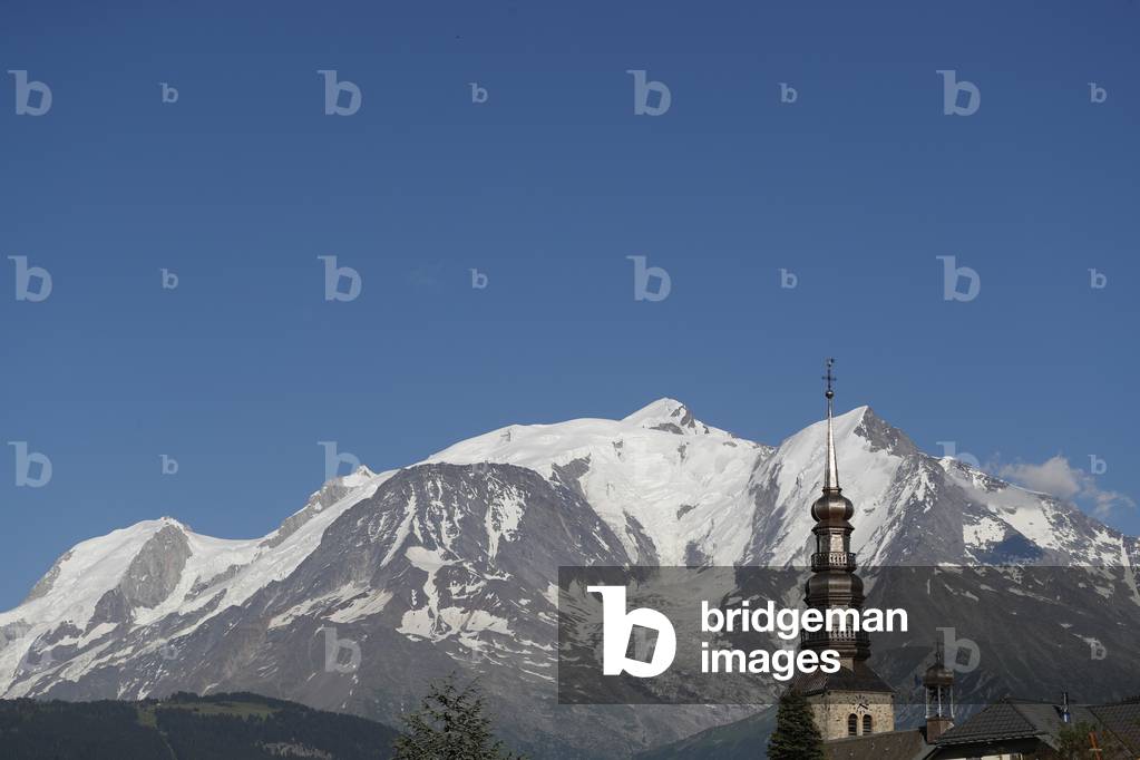 Baroque clock tower of Saint Nicolas church against Mont-Blanc massif in the french Alps.  Combloux. France.