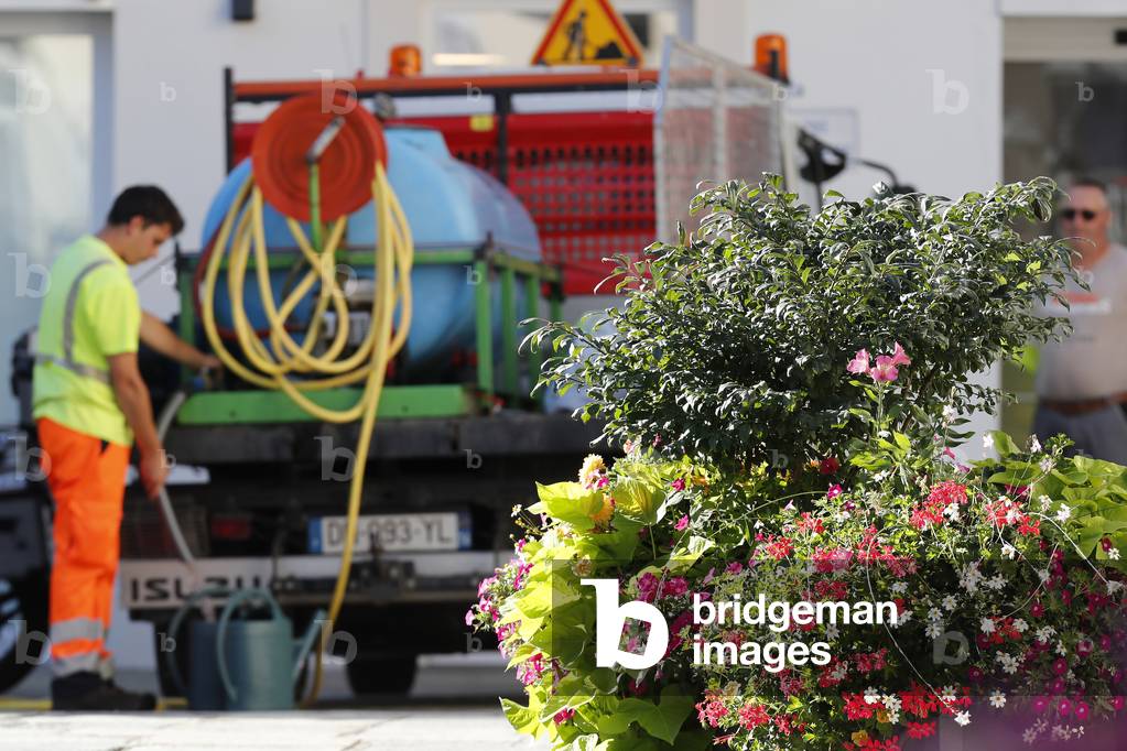 Colourful flowers in the village of Saint Gervais les Bains in the French Alps. Gardener watering flowers. France.