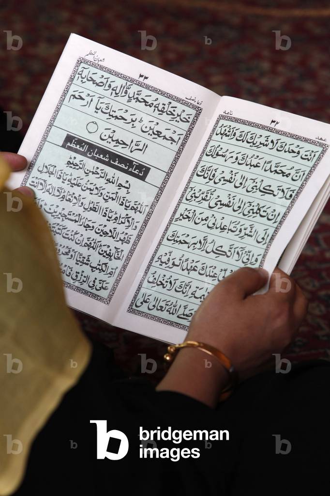 Woman reading scriptures in Nizamuddin Dargah complex Delhi Inde