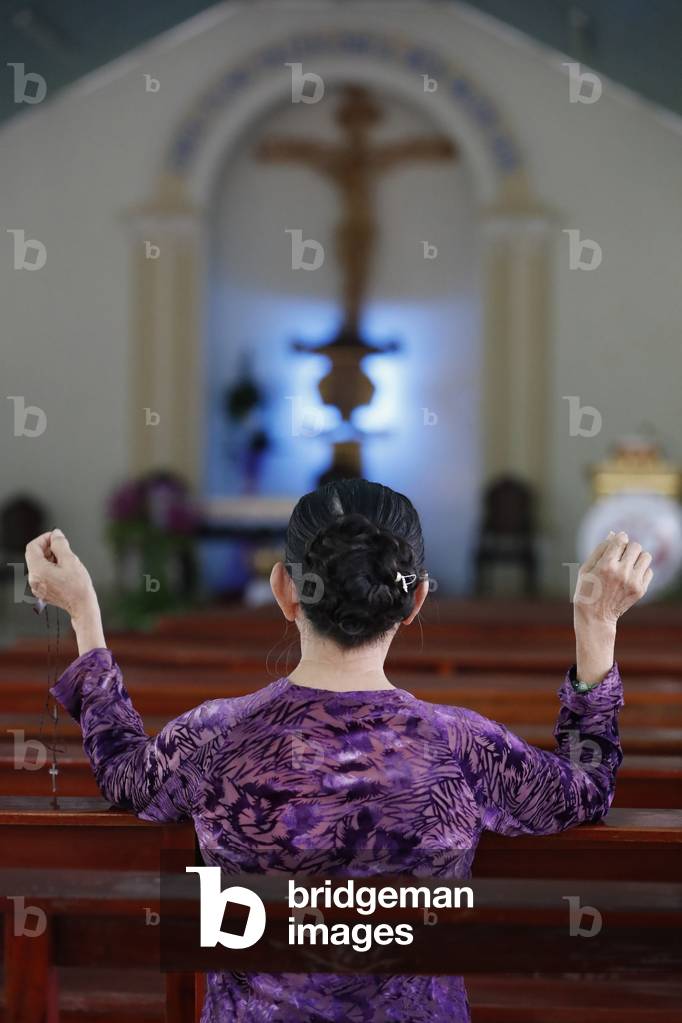 Woman praying in a catholic church, Basilica of Our Lady of La Vang, Pilgrimage, La Vang, Vietnam, 2019 (photo)