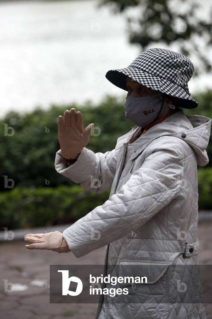 Woman do Tai Chi in the morning on the banks of Hoan Kiem Lake, Hanoi, Vietnam (photo)