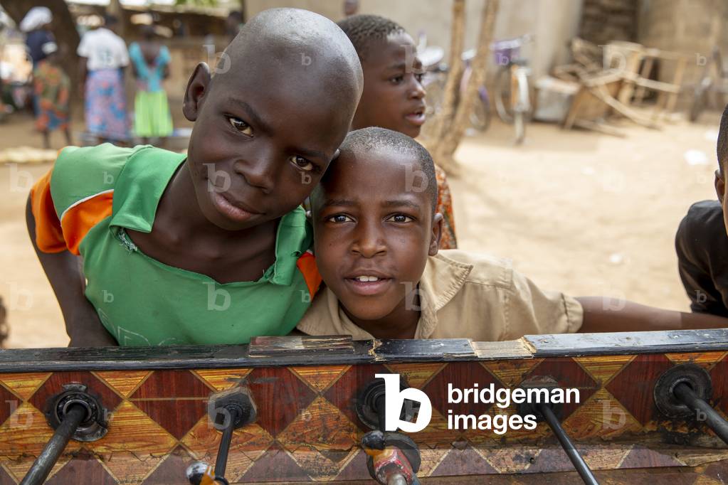 Togolese boys leaning on a table football in Korbongou, Togo, 2019 (photo)
