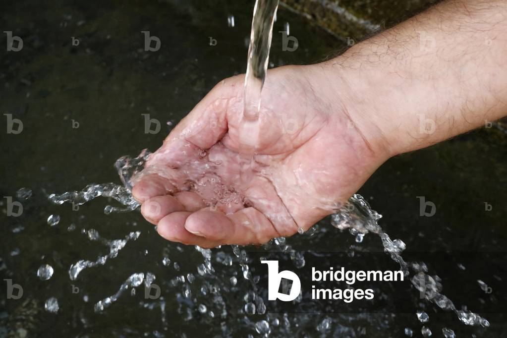 Fresh water flowing from a fountain in the hand of a man.  France.