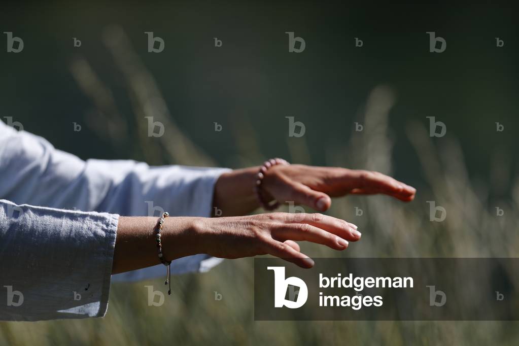 Woman practicing Qi Gong or Tai Chi exercise   in nature. Close up on hands.  France.