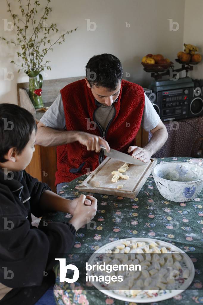 Young man showing his younger brother how to make gnocchi. Eure, France.