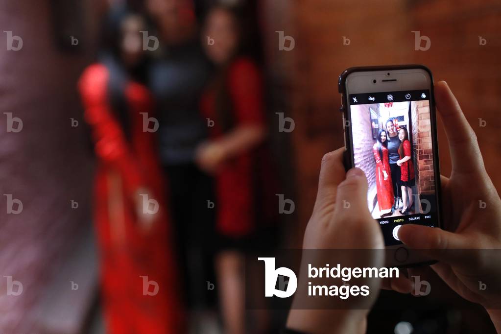 Vietnamese girls with traditional long dress Ao Dai doing pictures with a smartphone, Ho Chi Minh City, Vietnam (photo)