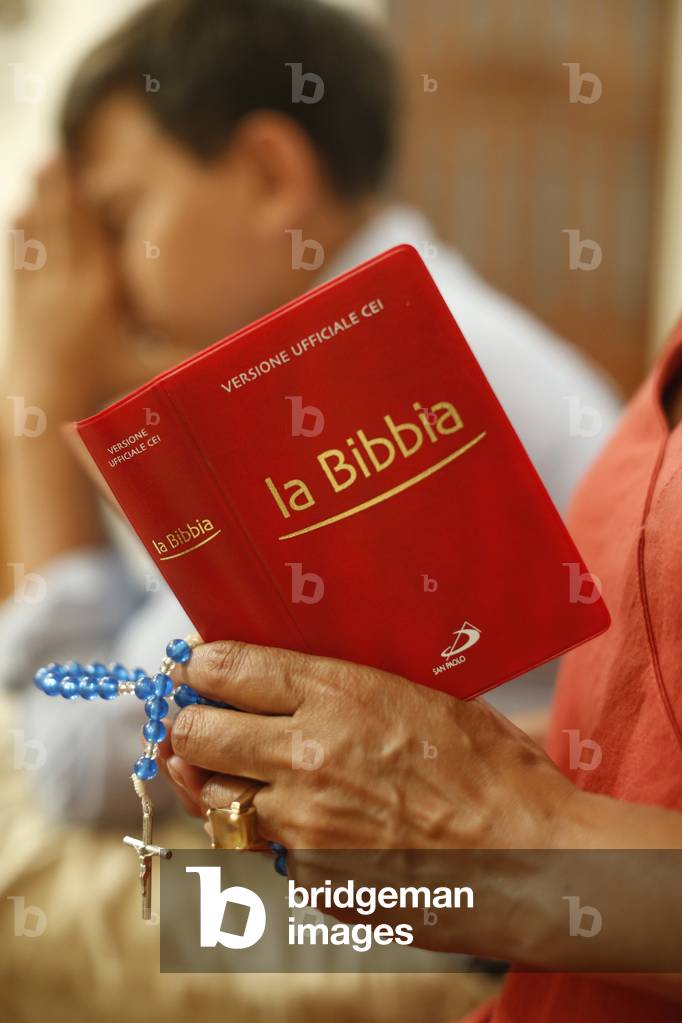 Mother and son reading the bible in a church in Lecce, Italy, 2019 (photo)