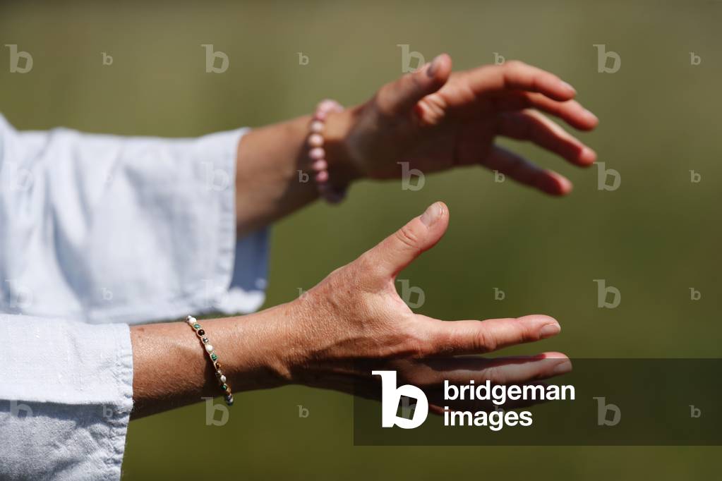 Woman practicing Qi Gong or Tai Chi exercise   in nature. Close up on hands.  France.