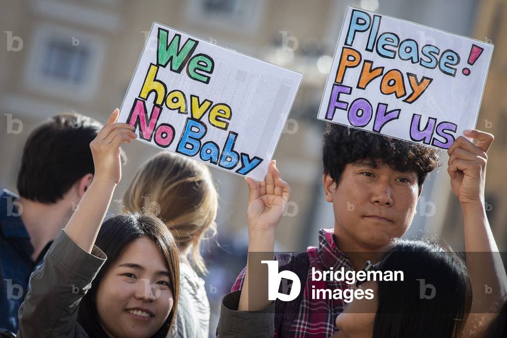 Couple holding signs while Pope Francis arrives for his weekly general audience in St. Peter's Square at the Vatican.