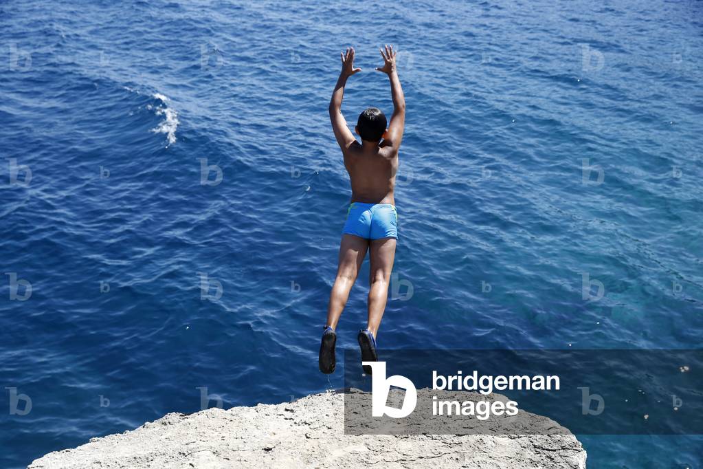 11-year-old boy jumping from a cliff into the sea in Salento, Italy (photo)