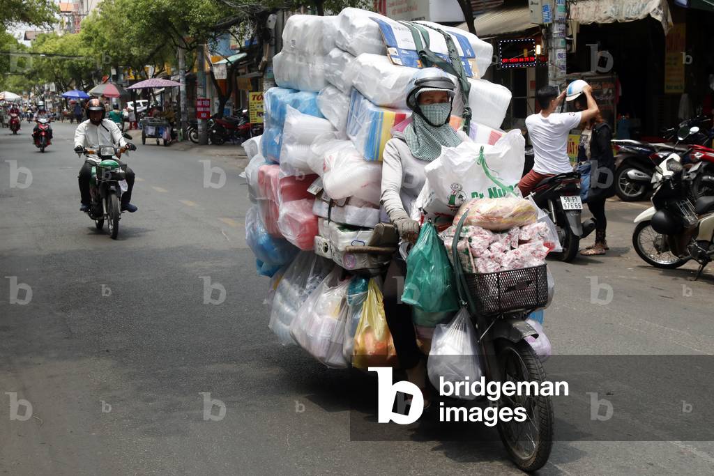 Woman driving a motorbike with big charge on Saigon Street, Ho Chi Minh City, Vietnam (photo)
